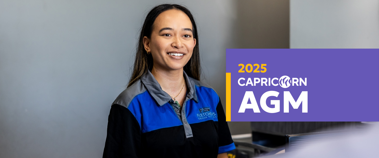 A person wearing a blue and black uniform stands smiling in front of a gray background. To the right, there is a purple and yellow graphic that reads '2025 Capricorn AGM.