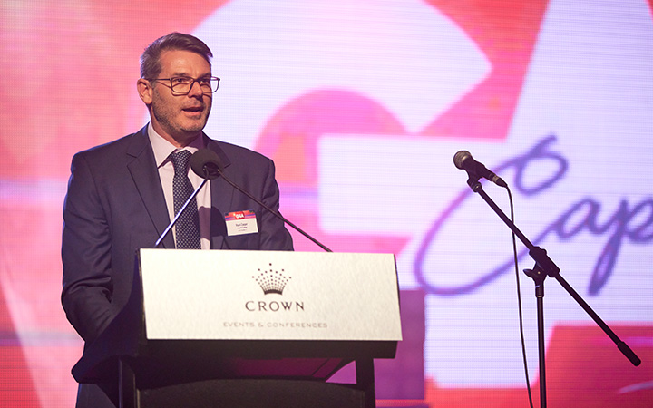 A Capricorn Member in formal attire stands at a stage, representing the Capricorn Member Director during a Gala Dinner event.