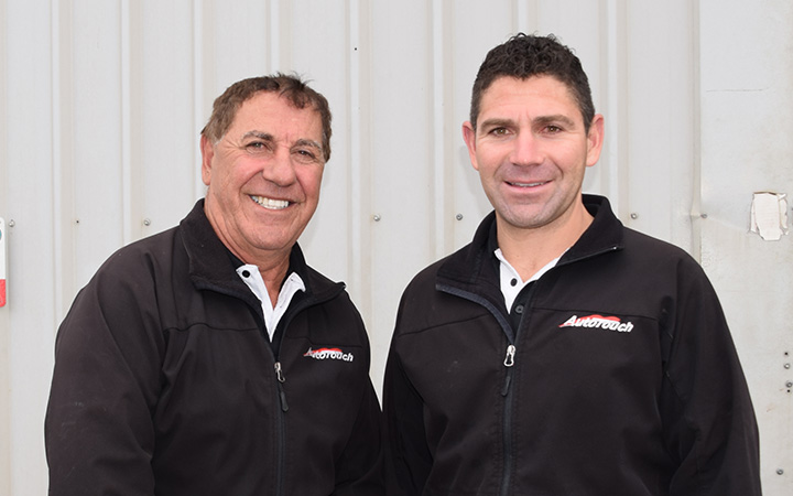 n front of the Autotouch workshop, Pino Priolo and his son Michael pose together, both smiling to the camera.
