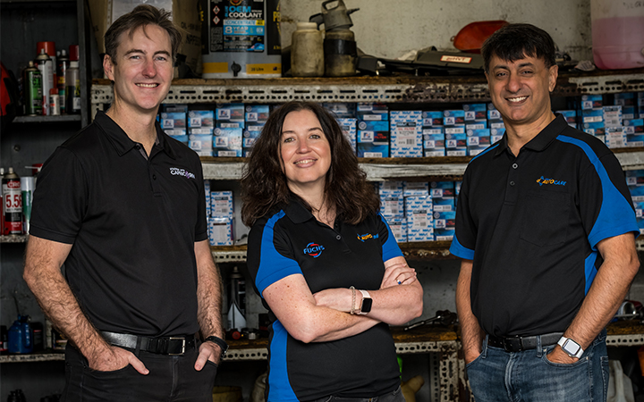 Brad Gannon, Moira and Patrick D'Cruz standing in a workshop smiling at the camera