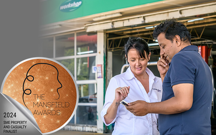 Capricorn Risk Account Manager talks with a Member in front of his workshop with a sticker overlay saying 'The Mansfield Awards 2024 SME Property and Casualty Finalist.