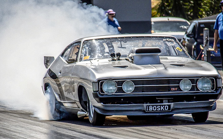 Drag car, Ford Falcon XA Coupe, billowing smoke on the track.