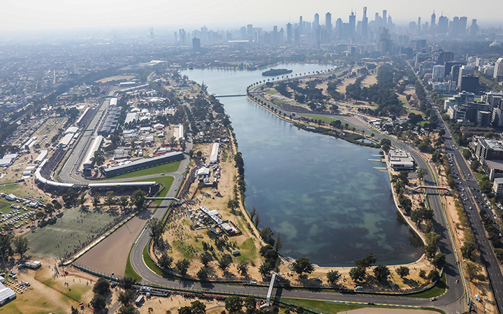 Aerial view of a city with a lake and a road, showcasing the Albert Park Circuit.
