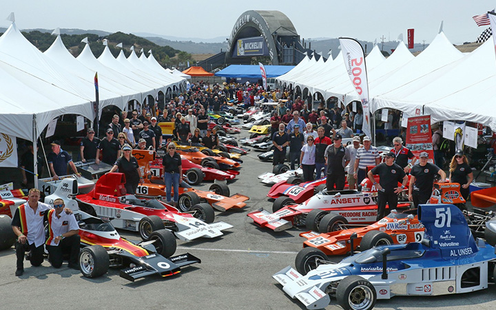People gathered around a lineup of race cars at the 2023 Rolex Monterey Motorsports Reunion