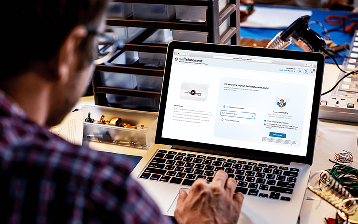 A person using a laptop displaying the SwiftStatement log in page