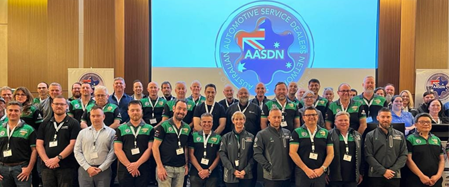 Members of the Australian Automotive Service Dealers Network, dressed in black and green shirts, standing together.