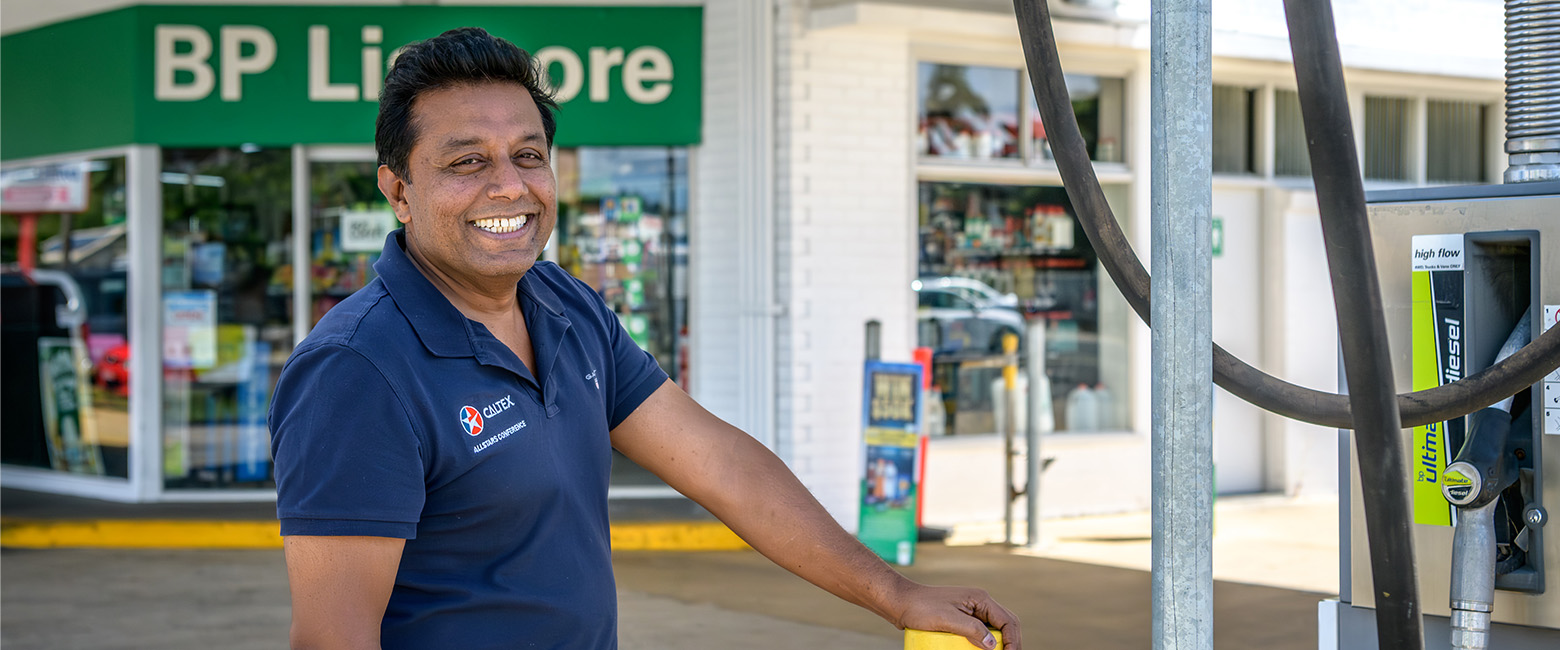 A man named Shahzad stands in front of his service station.