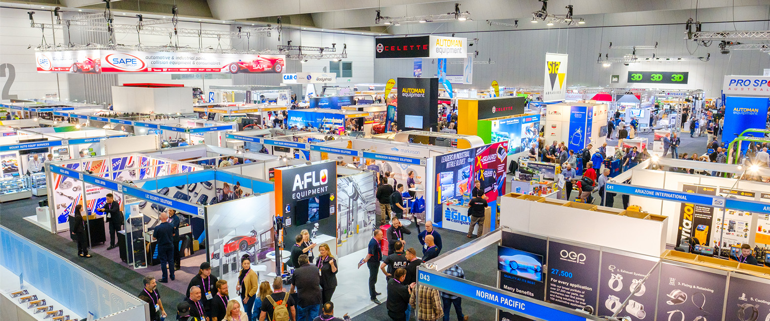 A crowded indoor exhibition hall with people walking around.